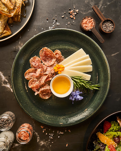 High-end, professional food photography for a boutique hotel. A beautifully plated signature dish (like a grilled steak or herb-crusted salmon) on a marble table with elegant glassware and warm, ambient lighting. Sophisticated and inviting atmosphere. 8k resolution, cinematic lighting.