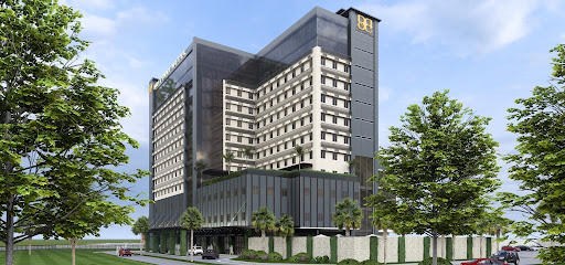 A grand cinematic wide shot of a luxury hotel facade at twilight. The building features elegant Mediterranean-inspired architecture with warm glowing lights in every window, reflecting off a pristine infinity pool in the foreground. The sky is a deep indigo, contrasting with the warm cream and gold tones of the structure, creating an atmosphere of sophisticated European coastal luxury.