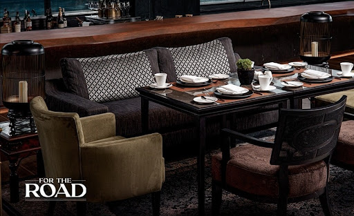 An elegant, dimly lit fine dining space with plush velvet chairs and marble tables, capturing the essence of an intimate boutique culinary experience. The lighting is soft and atmospheric, utilizing low-key shadows to create a sense of privacy and luxury. The color scheme is centered on rich deep navy and warm wood tones, evoking a quiet sanctuary feel.